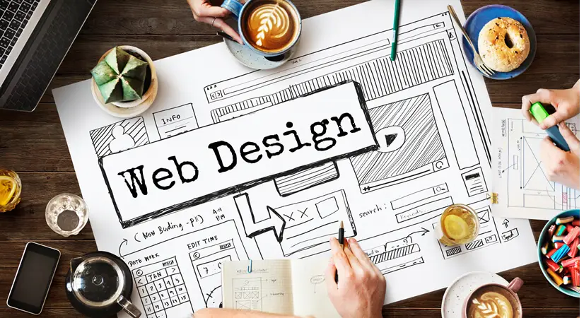 Creatieve webdesign-werkplek met schetsen van een website lay-out, koffie, pennen, notities en laptops. Handgetekende wireframes tonen elementen zoals menu’s, knoppen en paginablokken.